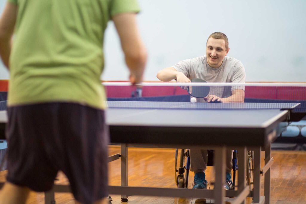 young man in a wheelchair is playing table tennis